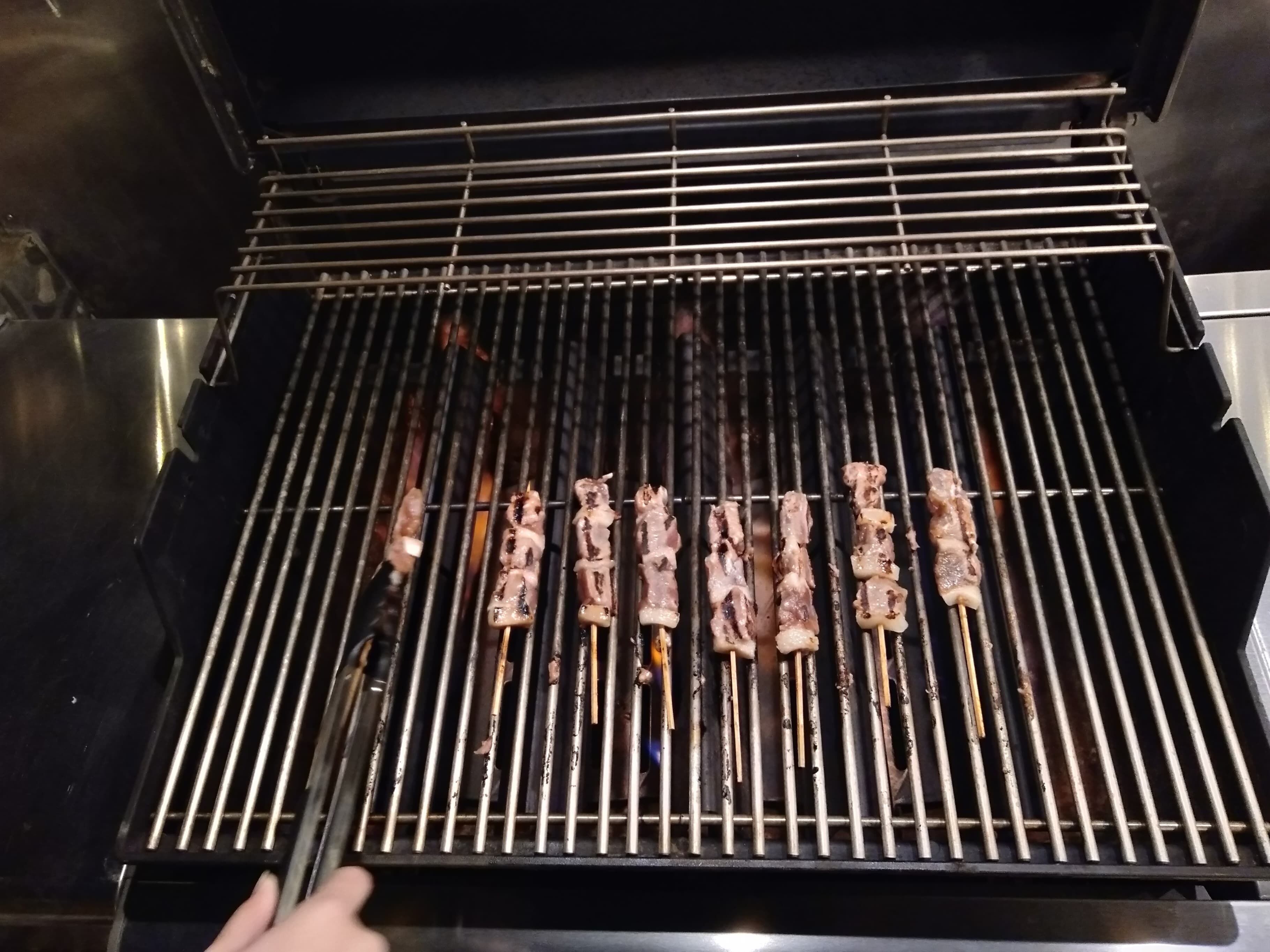 A grill with skewers of meat being cooked.