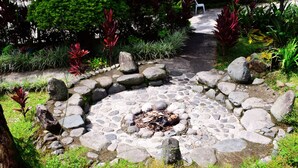 A stone fire pit surrounded by rocks and greenery in a garden setting. - Log Cabin Hotel-Baguio (Baguio)