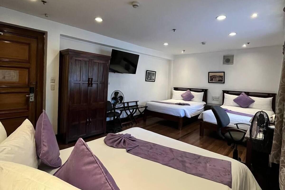 A hotel room with two beds, a TV, a desk, and a wardrobe.