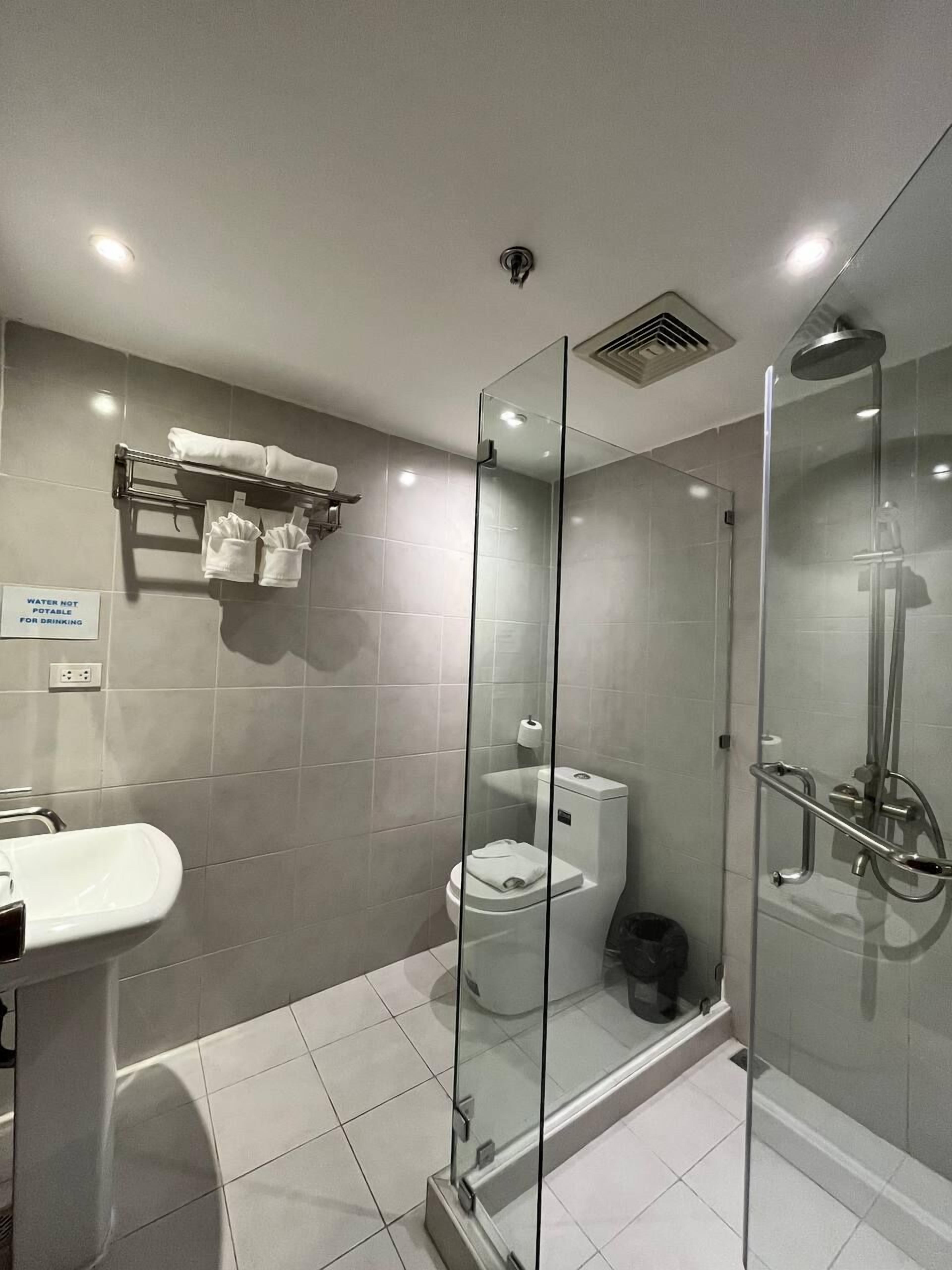 Ein modernes Badezimmer mit einer Duschkabine, einem weißen Waschbecken und einer Toilette.