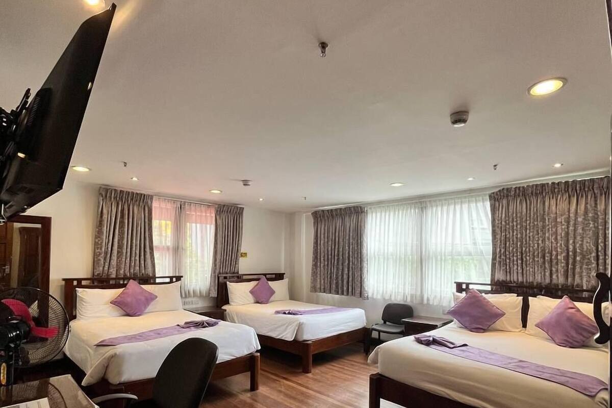 A hotel room with two beds, a desk with a computer, a chair, and a TV.