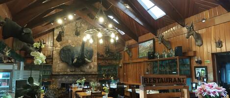 Un restaurante con interiores de madera, trofeos de animales en la pared y un letrero que indica que es un restaurante.