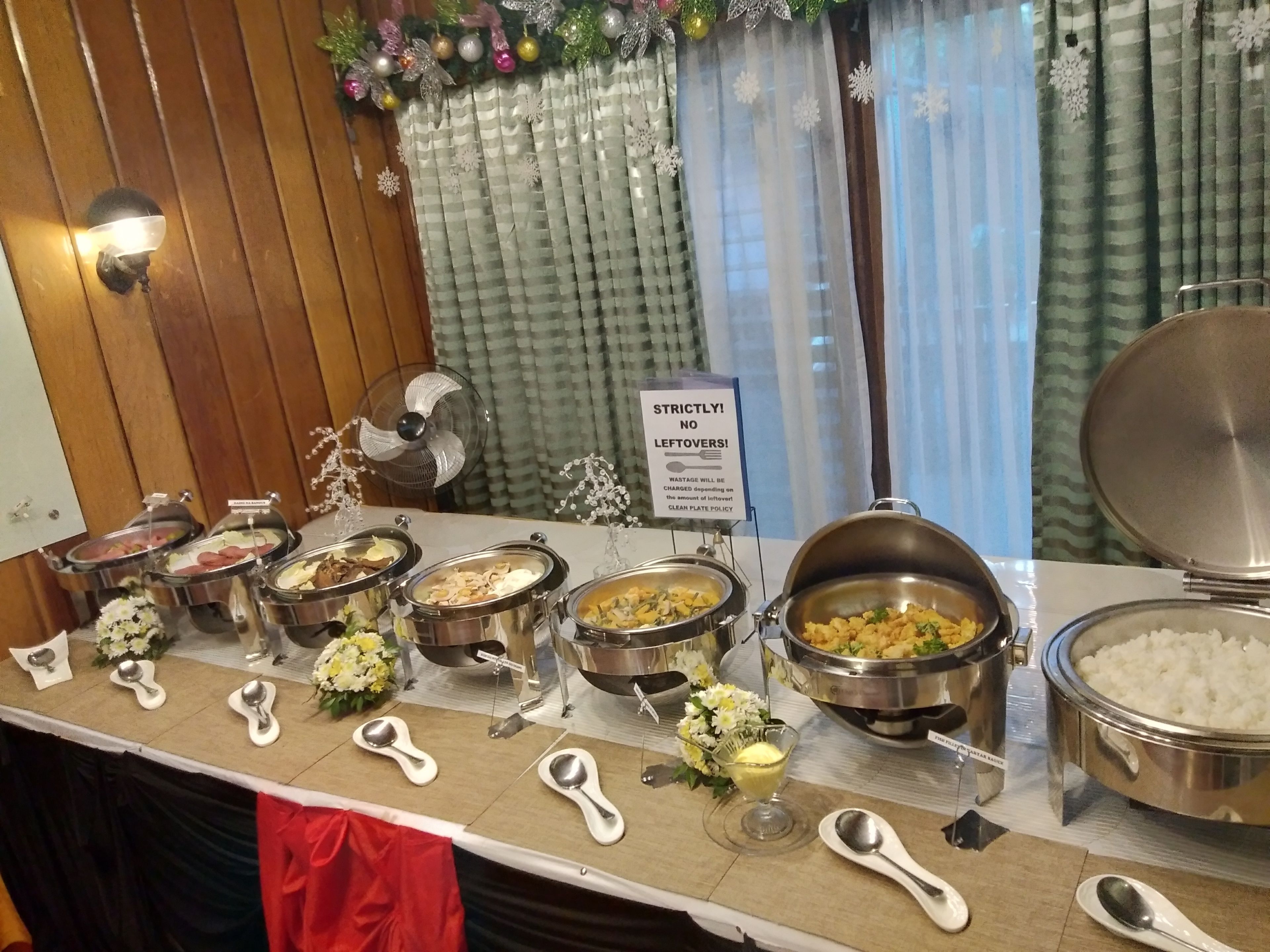 A buffet setup with multiple food containers and serving utensils.