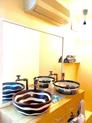 Um banheiro com três pias listradas em preto e branco, um espelho e um porta-toalhas.
