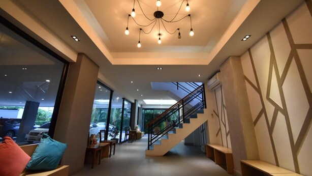 A spacious interior with a modern staircase, large windows, and a chandelier. - B Boutique Residence (Surat Thani)