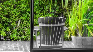 A modern outdoor seating area with a metal chair and table, surrounded by lush greenery. - B Boutique Residence (Surat Thani)