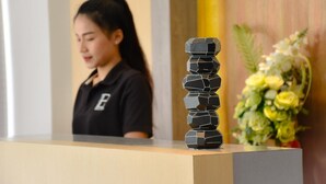 A reception desk with a decorative stack of black geometric objects and a floral arrangement in the background. - B Boutique Residence (Surat Thani)