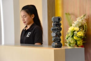 A reception desk with a decorative stack of black geometric objects and a floral arrangement in the background. - B Boutique Residence (Surat Thani)