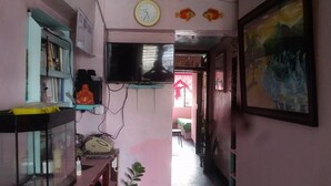 A narrow hallway with a television mounted on the wall, a clock, and a fish decoration. - CVNB Bed & Bath - Hostel (Baguio)