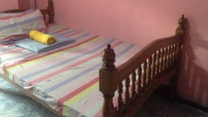 A bed with a striped bedspread, a rolled-up towel, and pillows. - CVNB Bed & Bath - Hostel (Baguio)