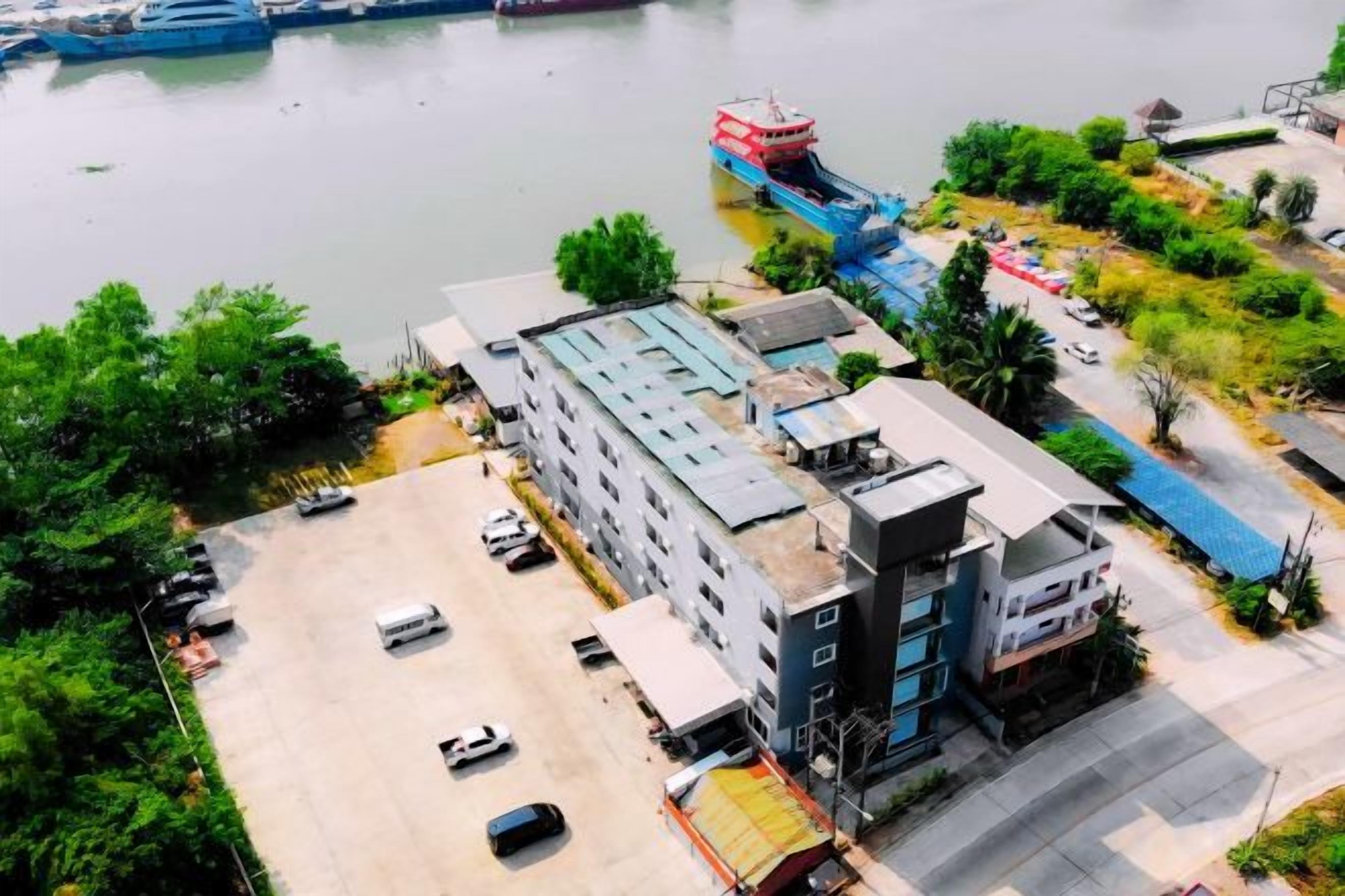 Un edificio de varios pisos con un estacionamiento y un río al fondo.