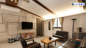 Un salon moderne doté d’un téléviseur à écran plat fixé au mur, d’une table basse en bois, de canapés en cuir et d’un style de décoration minimaliste.