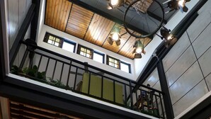 Un intérieur à plusieurs niveaux comprenant un espace repas, un escalier et un plafond orné de luminaires suspendus.