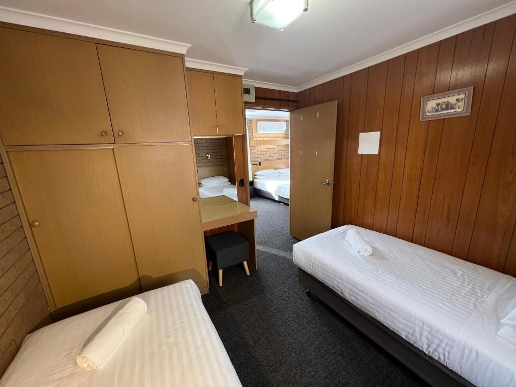A hotel room with two single beds, a desk, and a wardrobe.