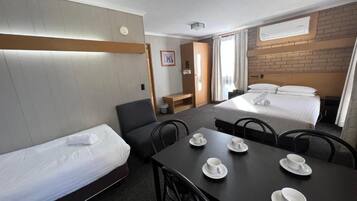 Ein Hotelzimmer mit einem Einzelbett, einem kleinen Tisch mit Tassen, einem Schreibtisch und einem Stuhl.