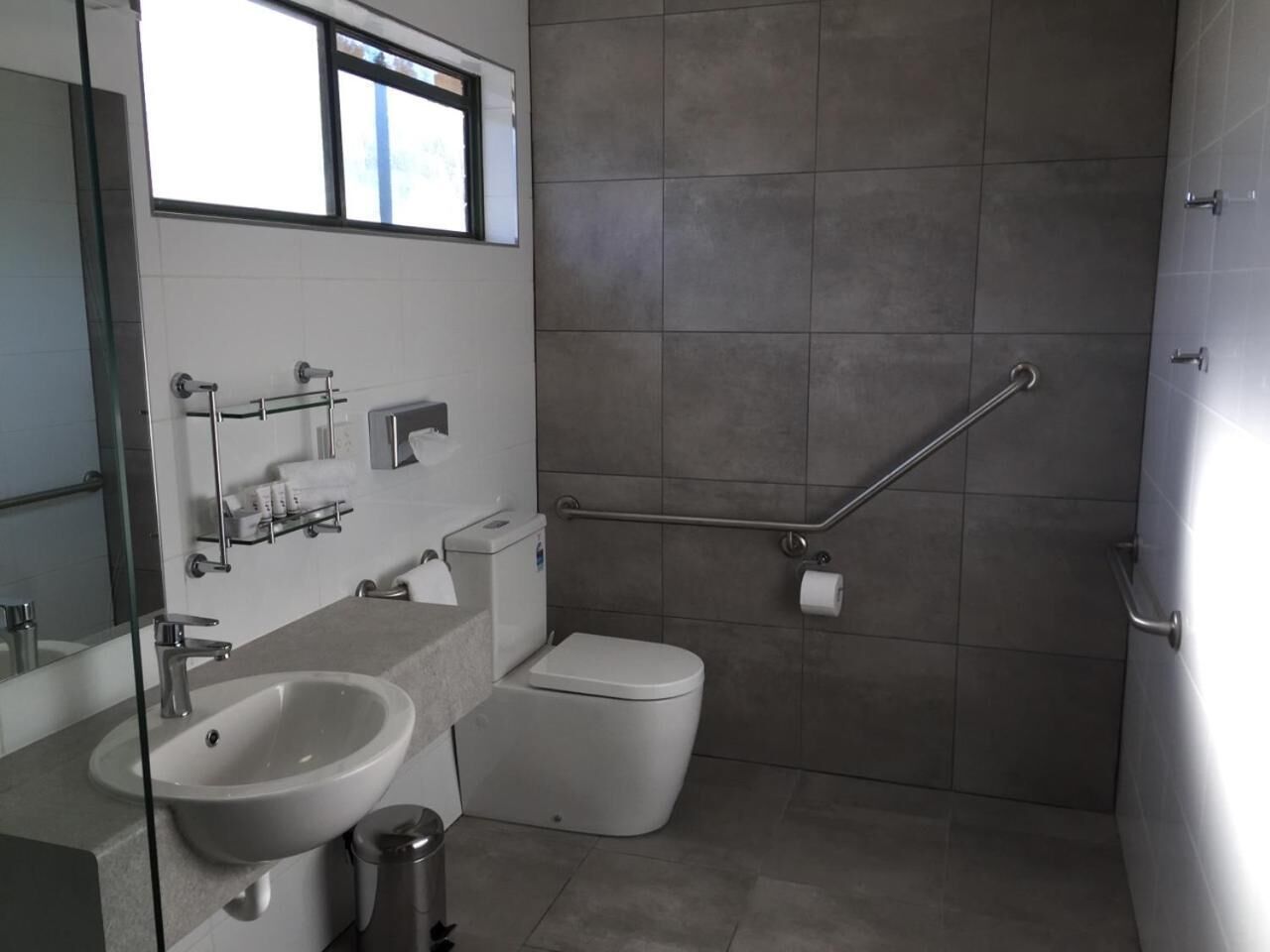Een moderne badkamer met een wastafel, toilet en douche.
