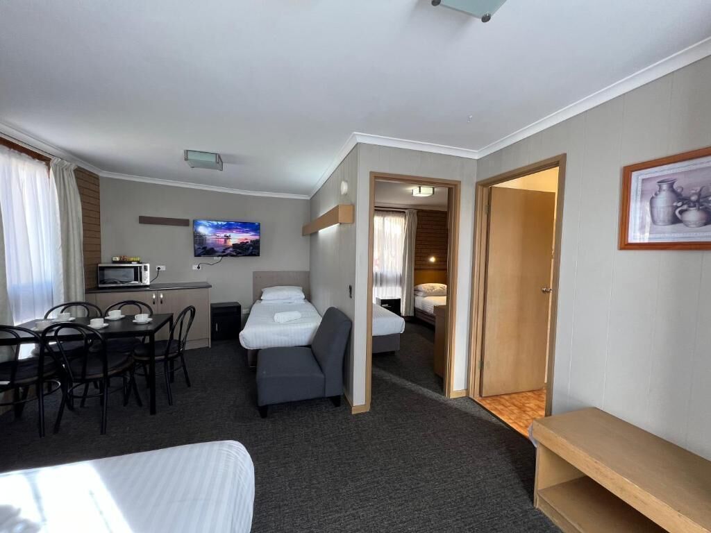 A hotel room with a bed, a desk with a chair, a television, and a microwave.