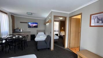 A hotel room with a bed, a desk with a chair, a television, and a microwave.