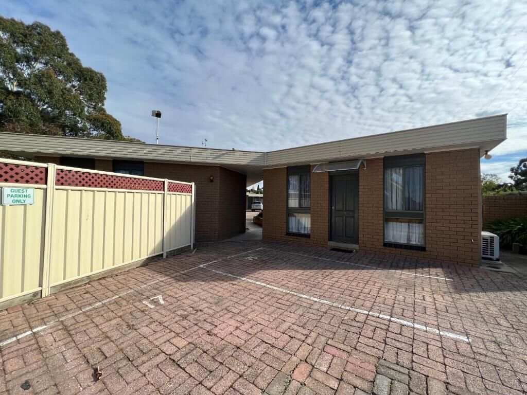 A building with a brick facade, a gated entrance, and a paved driveway.
