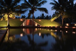 A nighttime view of a pool with palm trees and a lit structure in the background. - Blue Water Club Suites (Wadduwa)