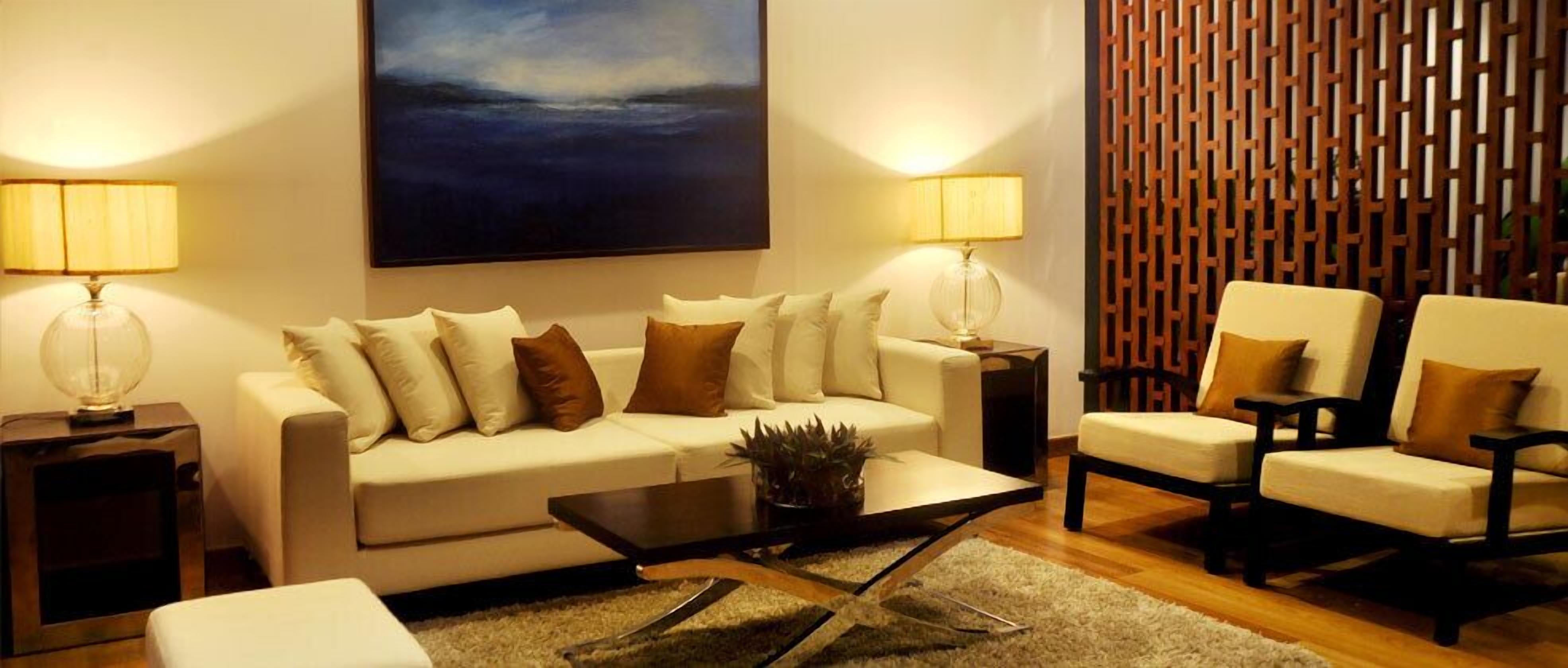 A modern living room with a sofa, armchairs, a coffee table, and two lamps.