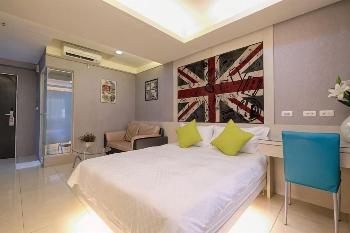 A modern bedroom with a large bed, a desk, and a chair.