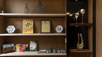A wooden shelf with various items including books, framed certificates, and decorative objects.