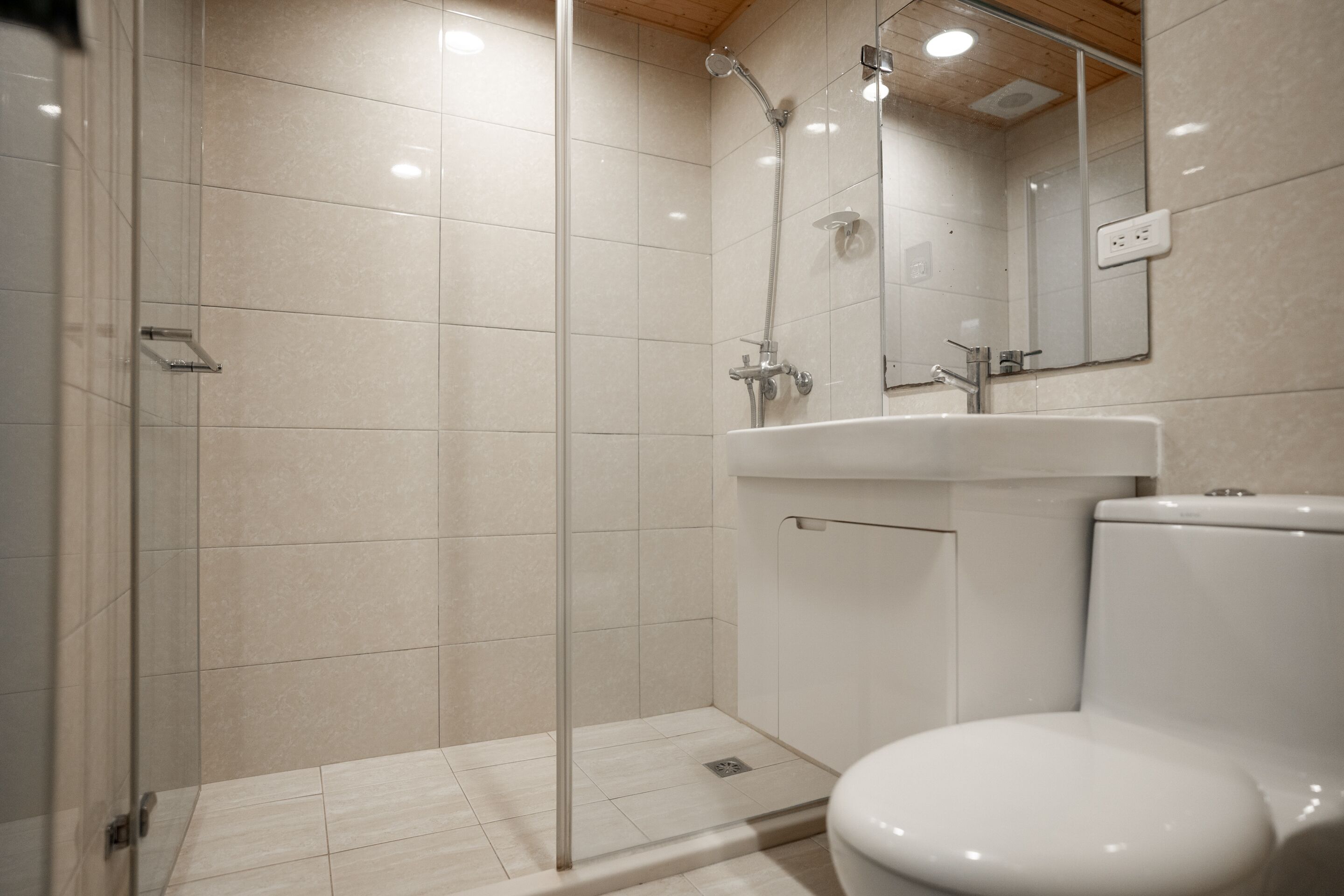 Une salle de bain avec une douche à parois de verre, des toilettes blanches et un lavabo avec un miroir au-dessus.