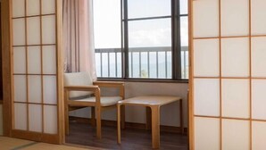Una habitación con suelo de tatami, una mesa baja de madera, una silla acolchada y un panel corredizo shoji.