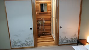 Habitación tradicional japonesa con puertas correderas, una pequeña escalera de madera, un lavamanos y un espejo.