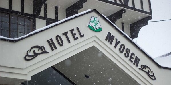 Une enseigne d’hôtel portant le nom « HÔTEL MYOSEN » et un logo au-dessus.