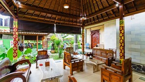 Un área de estar interior con muebles de madera y suelo de baldosas.