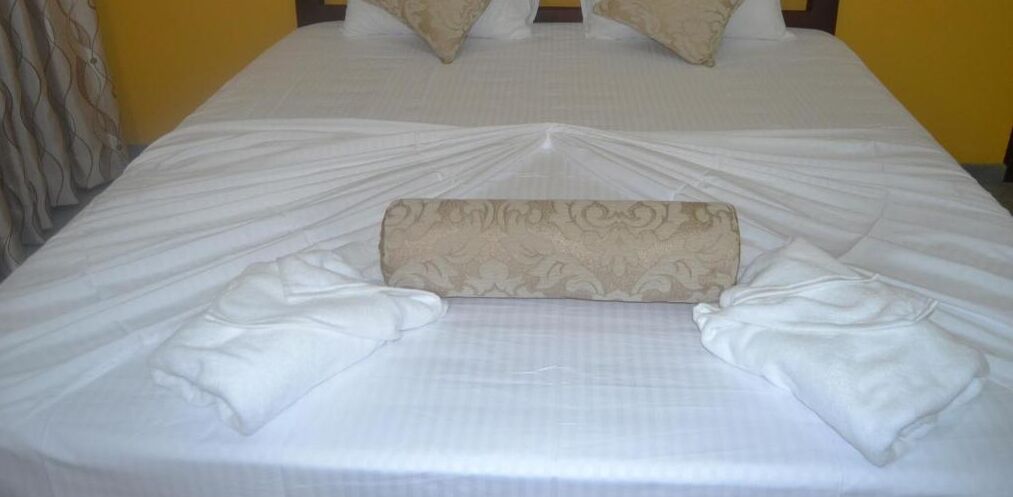 A neatly made bed with a patterned pillow and two folded pillows on either side.