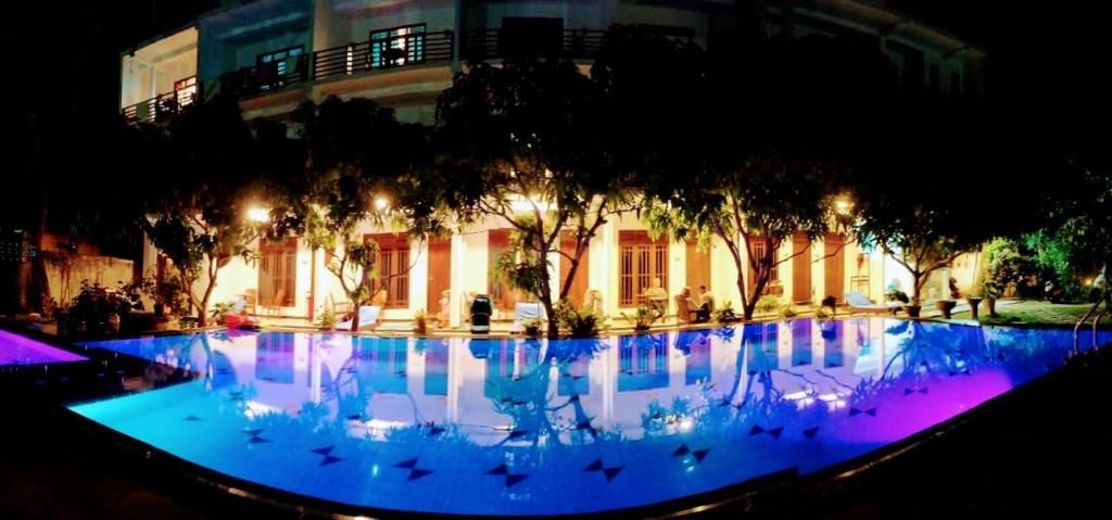 Una piscina con el reflejo de árboles y un edificio al fondo.