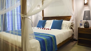 Ein Bett mit Baldachin, blaue Kissen und einer Blumenkomposition.