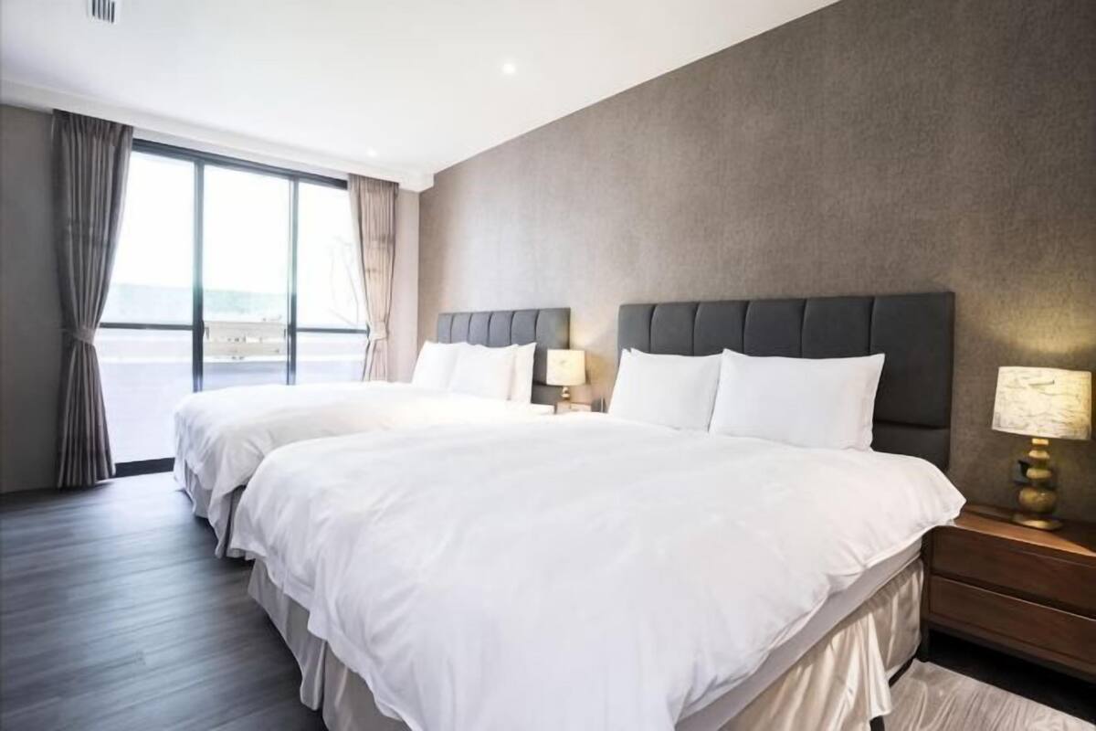 Une chambre d’hôtel avec deux lits, une grande fenêtre et une vue sur l’extérieur.