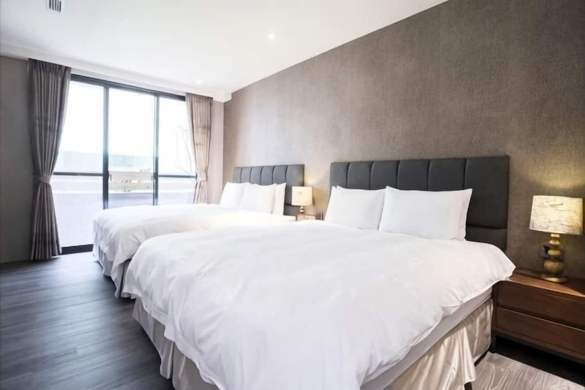 A hotel room with two beds, a large window, and a view of the outdoors.