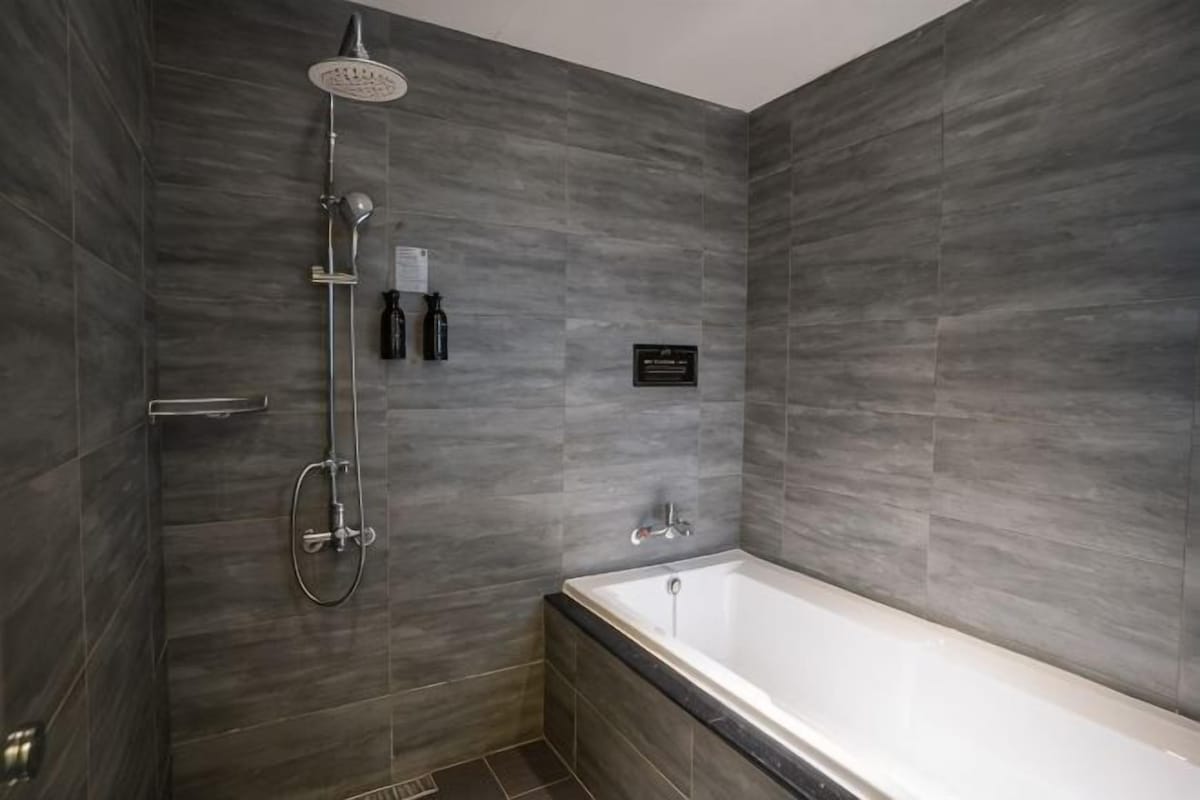 Une salle de bain moderne équipée d’une douche, d’une baignoire et d’un meuble-lavabo fixé au mur.