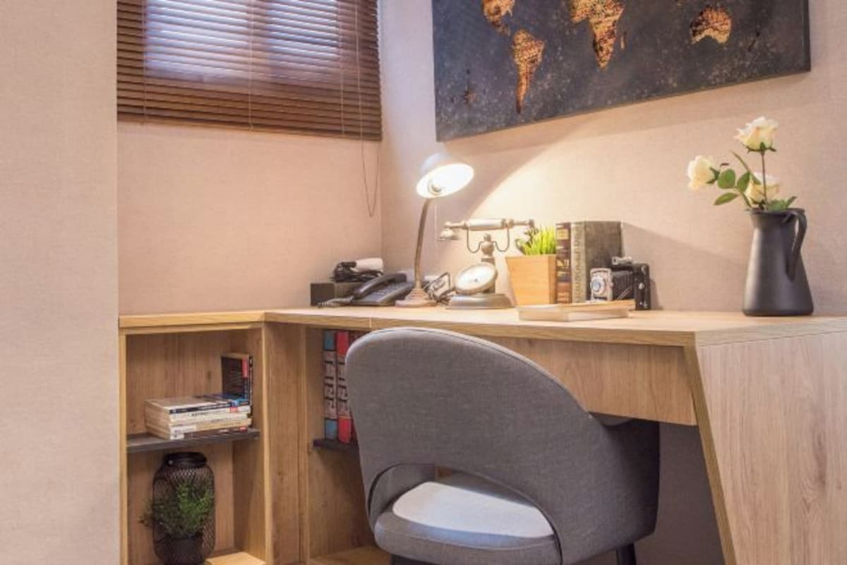 Un espacio de trabajo con escritorio, silla, lámpara, libros y objetos decorativos.