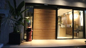 A modern building with a wooden exterior and glass doors leading to an interior with a reception desk and seating area. - Royal Rose Hotel Shuangcheng Hall (Taipei)