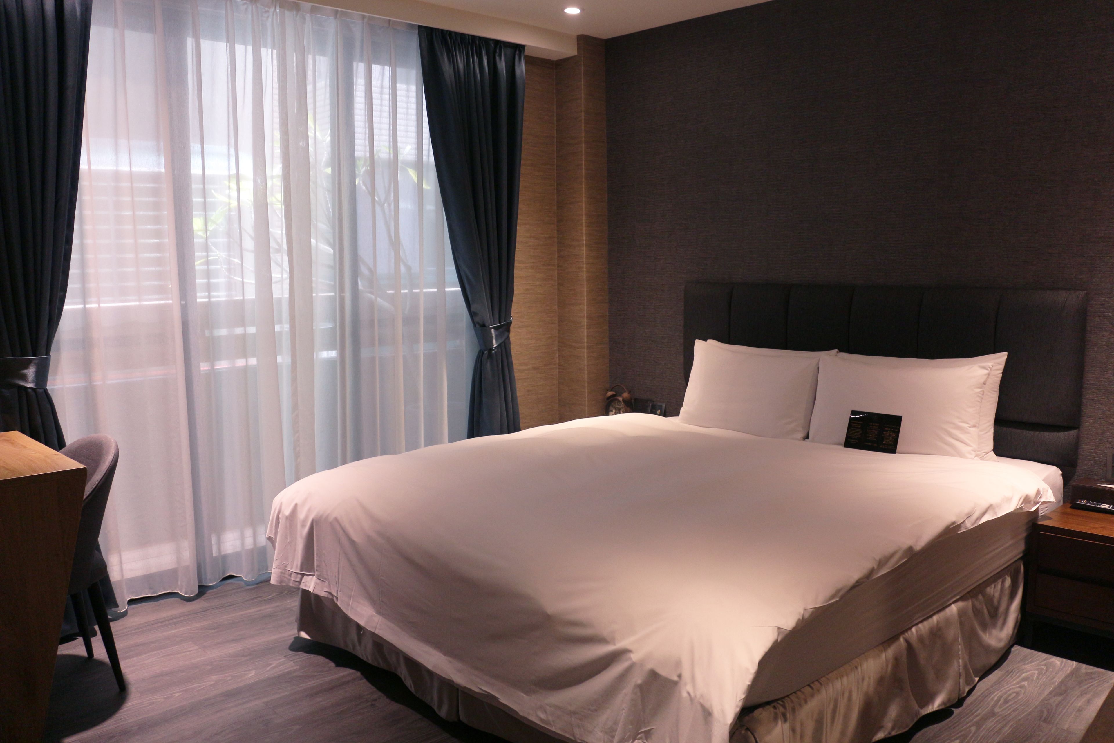 A hotel room with a large bed, a desk, and a chair.