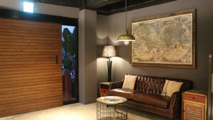 A room with a wooden sliding door, a leather sofa with a map on the wall, a lamp, and a small round table. - Royal Rose Hotel Shuangcheng Hall (Taipei)