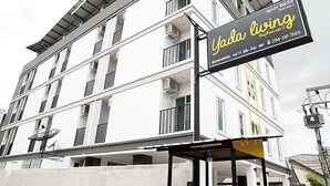 A multi-story building with a sign for 'Yada Living' featuring contact information. - Yada Living (Surat Thani)
