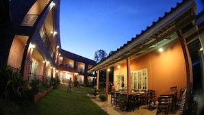 A multi-story building with outdoor seating and a well-lit patio area. - Le Bar Tarry Hotel (Tha Li)