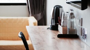 Una kitchenette con cafetera, hervidor y una botella de agua sobre la encimera.