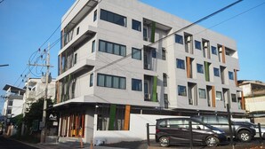 Un edificio moderno de varios pisos con fachada plana, ventanas grandes y una entrada visible con un letrero.