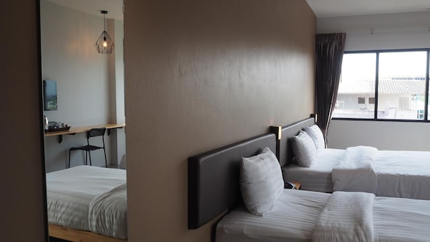 Habitación de hotel con dos camas, un espejo grande, un escritorio y vistas a edificios.