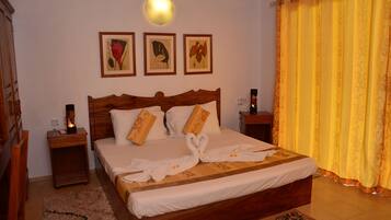 A neatly made bed with a wooden headboard, two bedside tables with lamps, and three framed artworks on the wall.