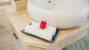 Un lavamanos blanco con una rosa sobre una bandeja azul en una encimera de mármol.