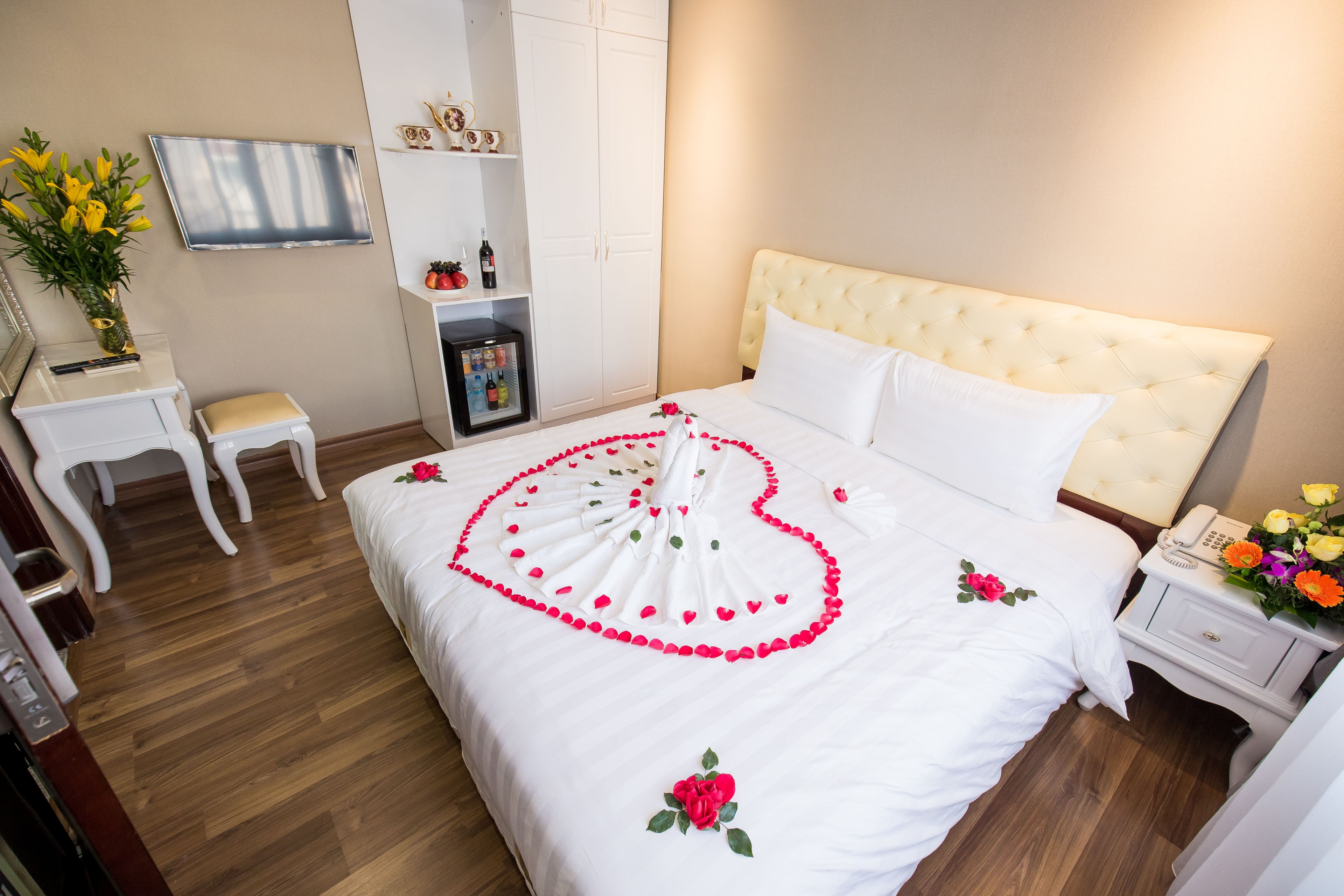 A neatly arranged hotel room with a bed, bedside table, and a small desk with a chair.